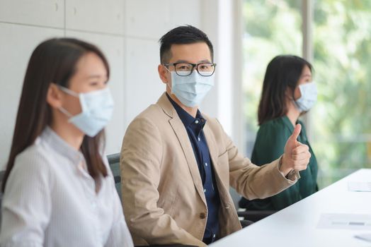 Business employees wearing mask during work in office to keep hygiene follow company policy.