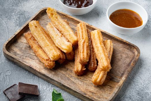 Typical Spanish snack churros, fried-dough pastry served usually with chocolate caramel hot sauce, on gray background