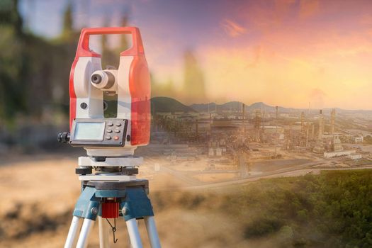 Double exposure surveyor equipment theodolite outdoors with panorama view of oil and gas refinery plant of petroleum or petrochemical industry production construction engineering work concept