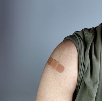 Band aid on male upper arm after covid 19 vaccine shot