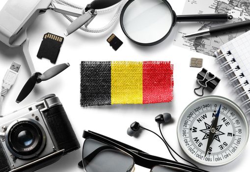 Flag of Belgium and travel accessories on a white background.