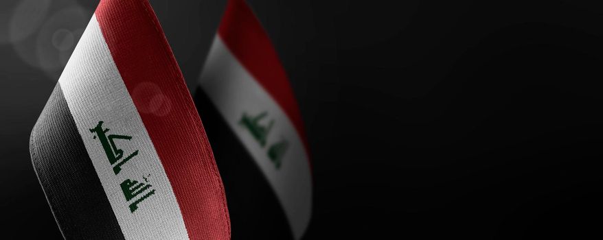 Small national flags of the Iraq on a dark background