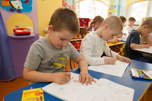 Belarus, the city of Gomel, April 25, 2019. Open day in kindergarten.Children draw. Preschoolers are engaged in a lesson.Boy with a pencil and an album.