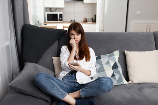 sad woman with phone in hand at home apartment communication. High quality photo