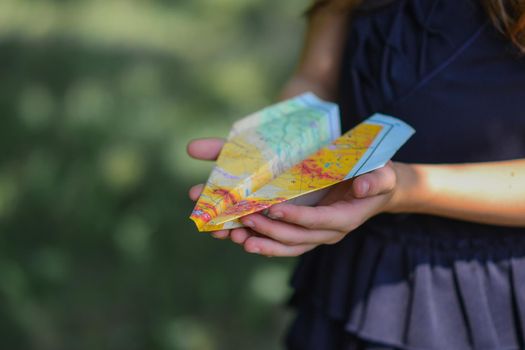 Girl holding paper airplane made of from the atlas of a geographical map.