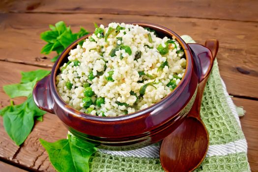 Couscous with spinach in bowl on board