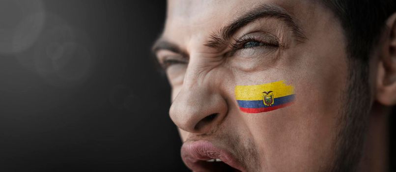 A screaming man with the image of the Ecuador national flag on his face