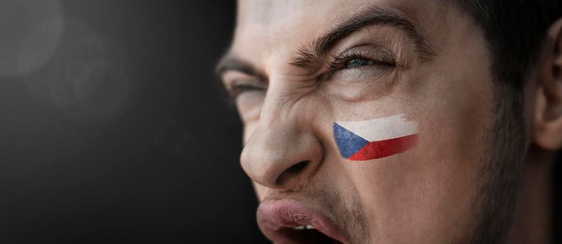 A screaming man with the image of the Czechia national flag on his face