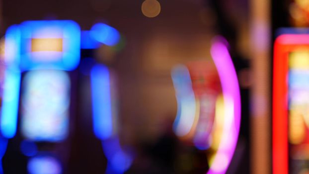 Defocused slot machines glow in casino on fabulous Las Vegas Strip, USA. Blurred gambling jackpot slots in hotel near Fremont street. Illuminated neon fruit machine for risk money playing and betting