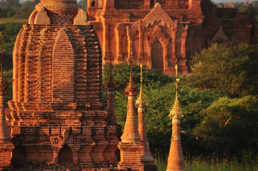 Beautiful brick temple in sunset light, Exterior view of old red brick temple with spires in green nature, Bagan, Myanmar, Mingalazedi Sulamani Shwezigon Ananda Htilominlo