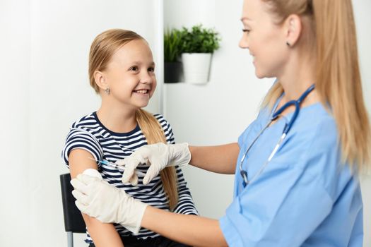 woman doctor in a blue coat injecting a child into the hand covid