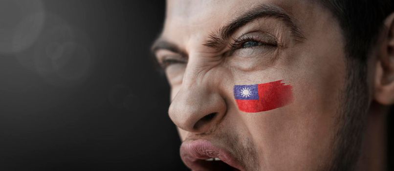 A screaming man with the image of the Taiwan national flag on his face