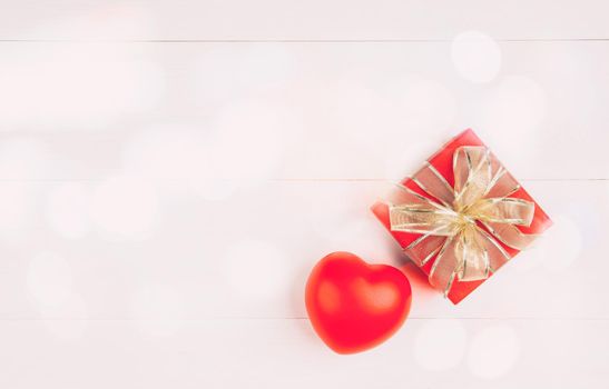 Red gift box and heart shape on wooden table background, love and romance, presents in celebration and anniversary with surprise on desk, happy birthday, donate and charity, valentine day concept.