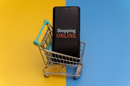 Shopping cart with smartphone. Online shopping concept.