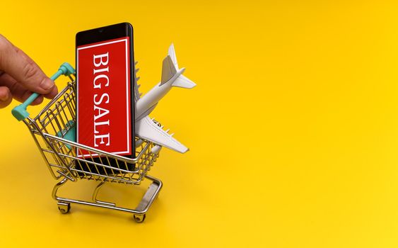 Shopping cart with plane toy. Air tickets sale concept.