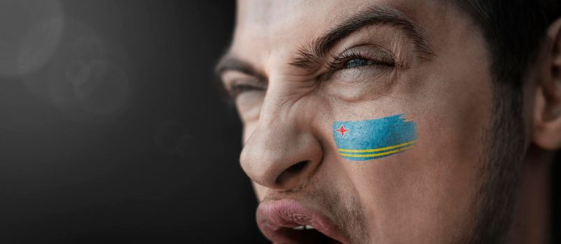 A screaming man with the image of the Aruba national flag on his face