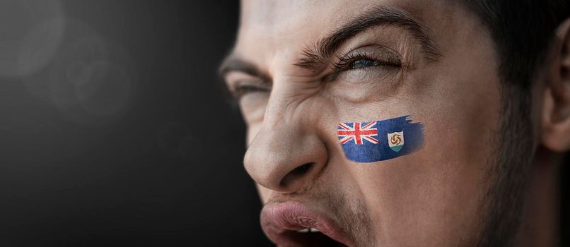 A screaming man with the image of the Anguilla national flag on his face