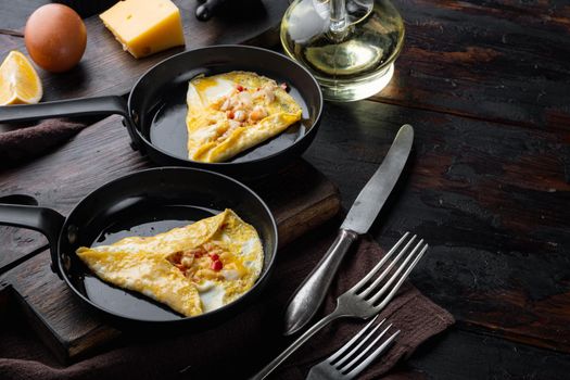 Spanish omelette, fresh red chilli, brown and white crabmeat, lemon, Cheddar cheese, eggs fried, on frying iron pan, on dark wooden background , with copyspace and space for text