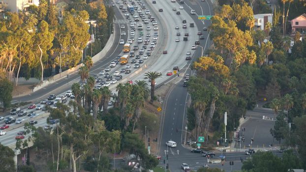Busy rush hour intercity highway in metropolis, Los Angeles, California USA. Urban traffic jam on road in sunlight. Aerial view of cars on multiple lane driveway. Freeway with automobiles in LA city