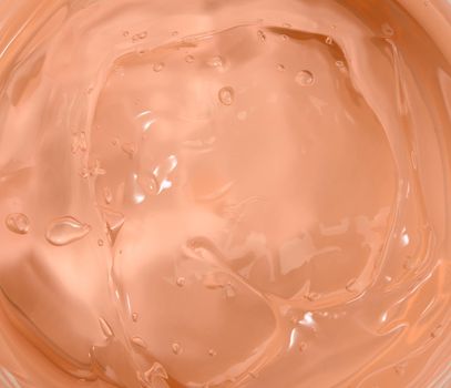 texture of orange moisturizing translucent cream in a plastic jar