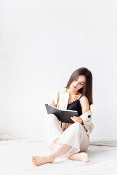 Beautiful woman in comfy home clothes writing notes sitting on the floor