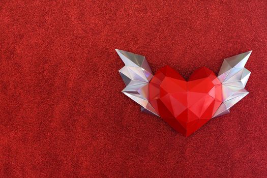 Polygonal heart with wings on a soft fleecy red background. copy space