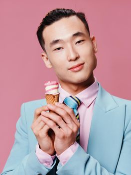 Cute man of asian appearance blue suit ice cream lifestyle close-up pink background enjoyment