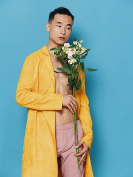 male korean appearance with a bouquet of flowers in a yellow coat and pink trousers