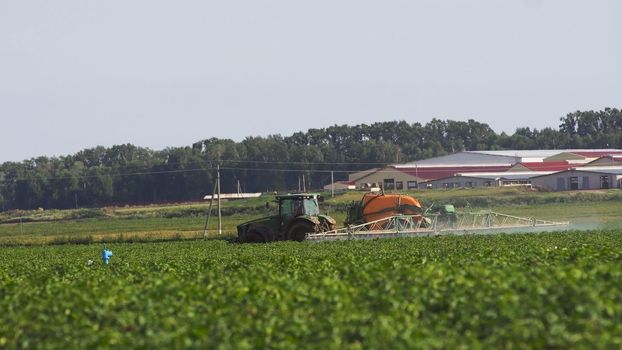 Tractor is spraying fertilizers field.
