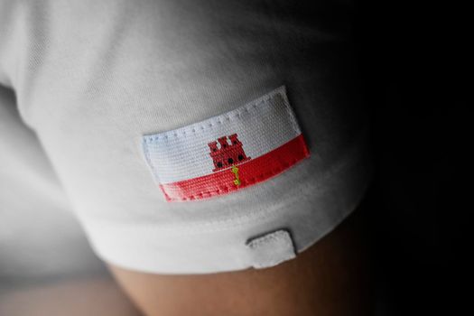 Patch of the national flag of the Gibraltar on a white t-shirt