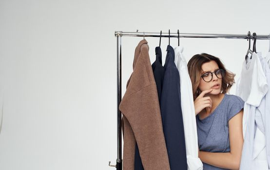 beautiful woman with glasses stands near clothes wardrobe suits Model