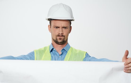 A man builder with a plan in the hands of a roll of paper white hard hat