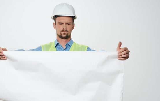 A man builder with a plan in the hands of a roll of paper white hard hat