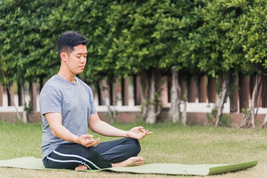 young man doing yoga outdoors in meditate lotus pose