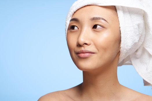 Asian woman naked shoulders and a towel on her head close-up