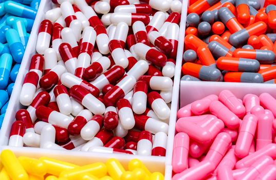 Capsule pills in plastic tray. Pharmaceutical industry. Drug production. Pharmaceutics concept. Vitamins and supplements capsules. Red, white, orange, gray, pink, yellow, and blue capsule pills.