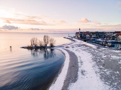 snow covered beach during wnter by Urk lighthouse in the Netherlands