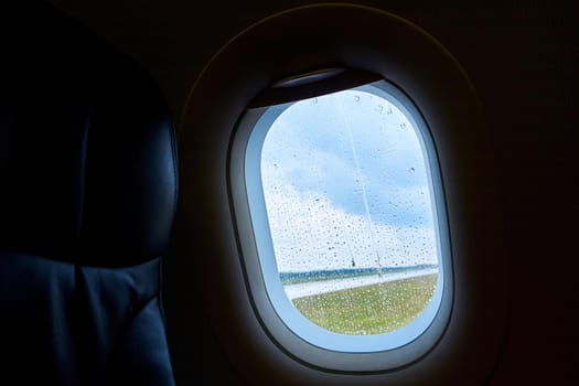 The interior of a passenger plane before takeoff. Porthole in raindrops