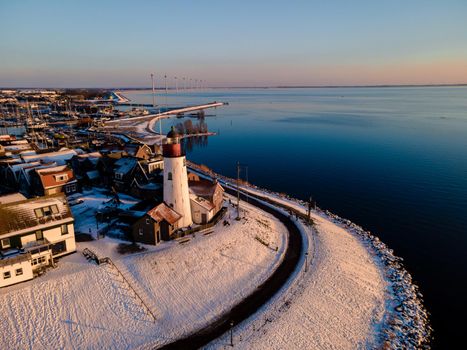 snow covered beach during wnter by Urk lighthouse in the Netherlands