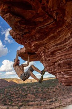 Carefree man is climbing on red sandstone rock of Nature's Window in Kalbarri National Park, Western Australia