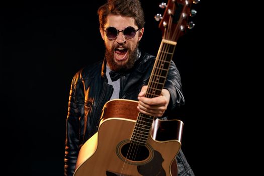 Cheerful man rock musician guitar playing music black background