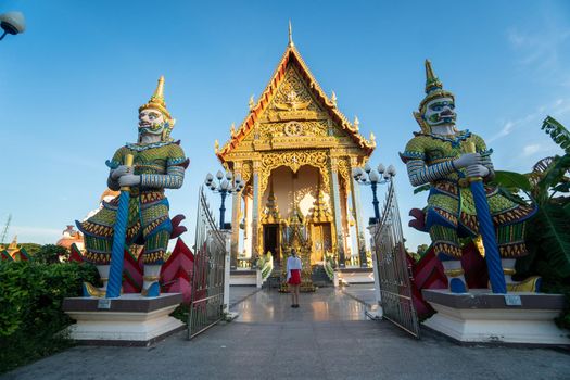 KOH SAMUI, THAILAND - January 10, 2020: Woman in a red dress stands in front of Ceremonial hall at the Wat Plai Laem Temple.