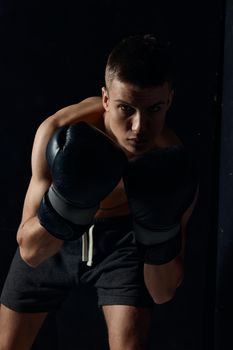 boxer in black gloves bent down on a dark background bodybuilder fitness workout