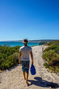 young caucasian man with a blue bag walking down a pathway to Hamelin Beach. This Beach is famous for his stingrays, Hamelin Beach, Western Australia
