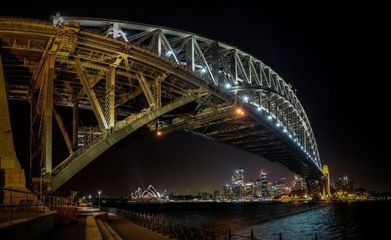 East side of Sydney harbour bridge at nihgt with bright reflecting in the blurred waters of harbour