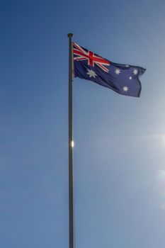 Australian flag slowly waving on the beautiful blue sky
