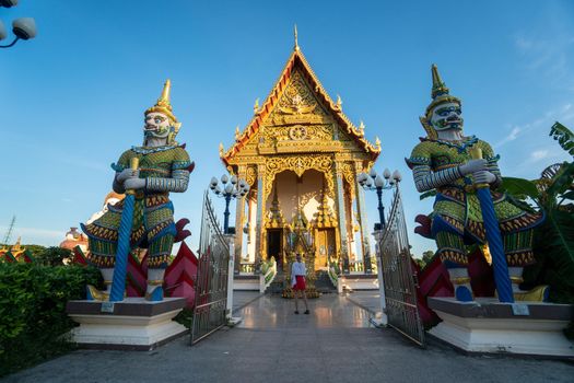 KOH SAMUI, THAILAND - January 10, 2020: Woman in a red dress stands in front of Ceremonial hall at the Wat Plai Laem Temple.