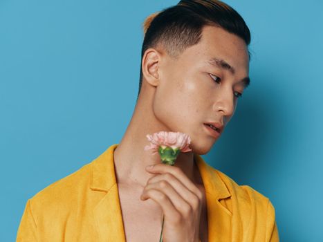 Handsome Asian man with flower romance blue background yellow coat. High quality photo