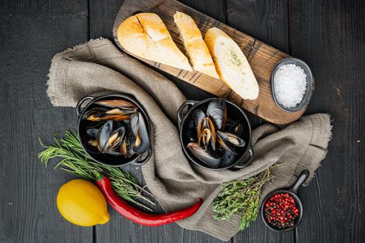 Boiled mussels in garlic sauce with parsley and ingredients, on black wooden table background, top view flat lay