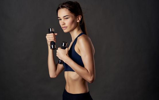 Woman with dumbbells fitness sport dark background slim figure. High quality photo